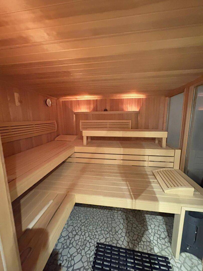 Geräumige Holzsauna mit mehreren Bänken und warmer Beleuchtung für Entspannung.