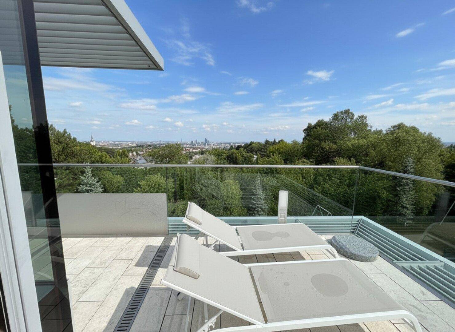 Geräumige Dachterrasse mit Liegestühlen und weitem Blick über die Stadt und grüne Umgebung.