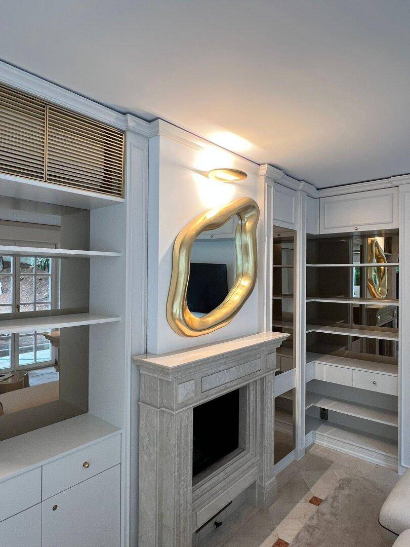 Stilvoller Wohnbereich mit dekorativem Kamin, eleganten Einbauschränken und modernem Spiegel.