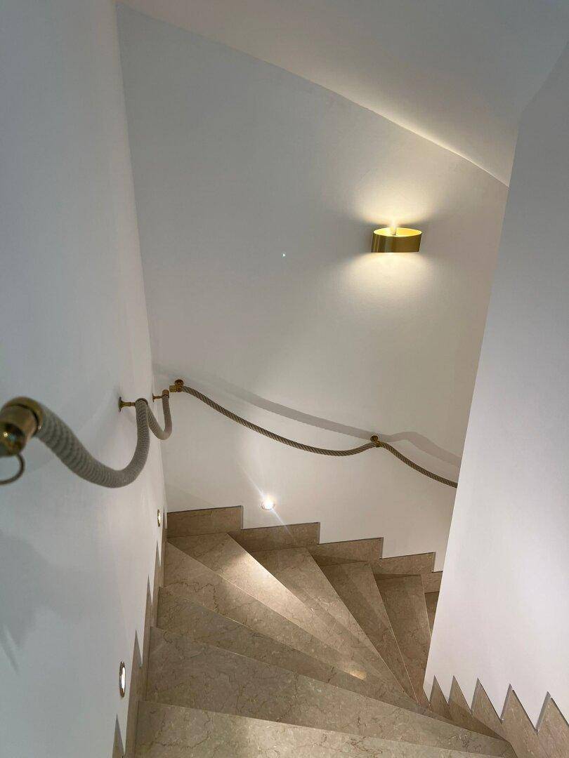 Elegantes Treppenhaus mit Marmorstufen und einem dekorativen Seilgeländer.