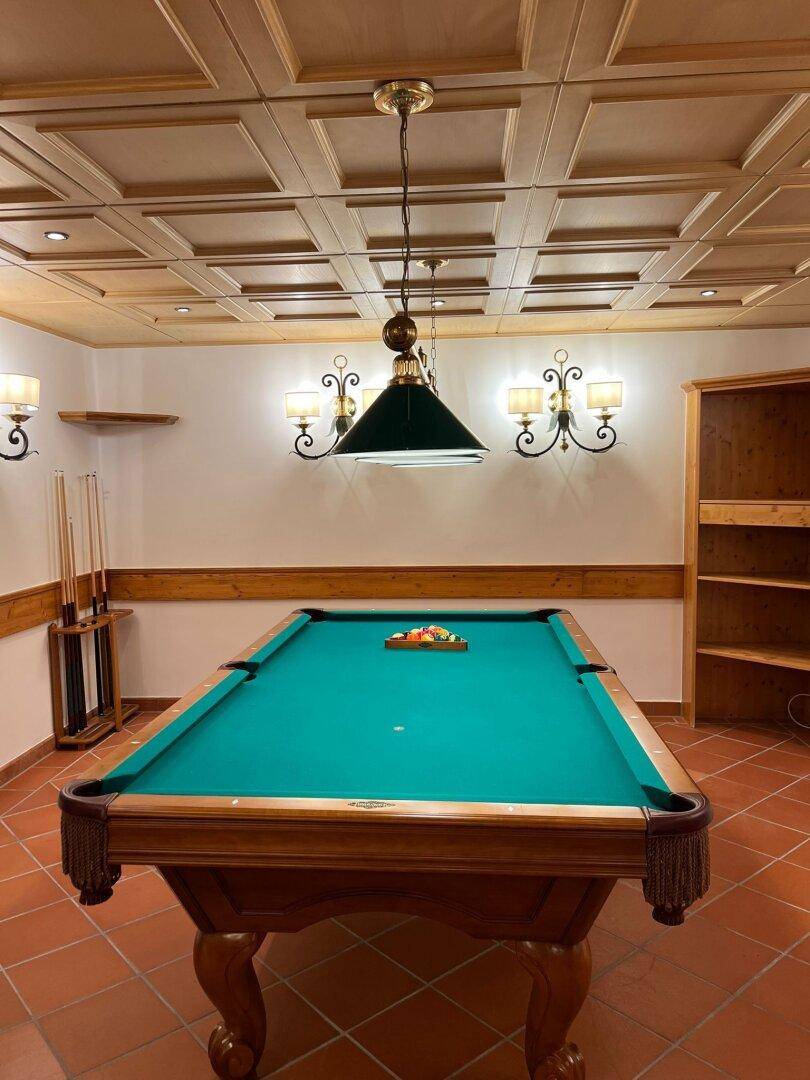 Geräumiger Spielraum mit Billardtisch, Holztäfelung und traditioneller Beleuchtung.