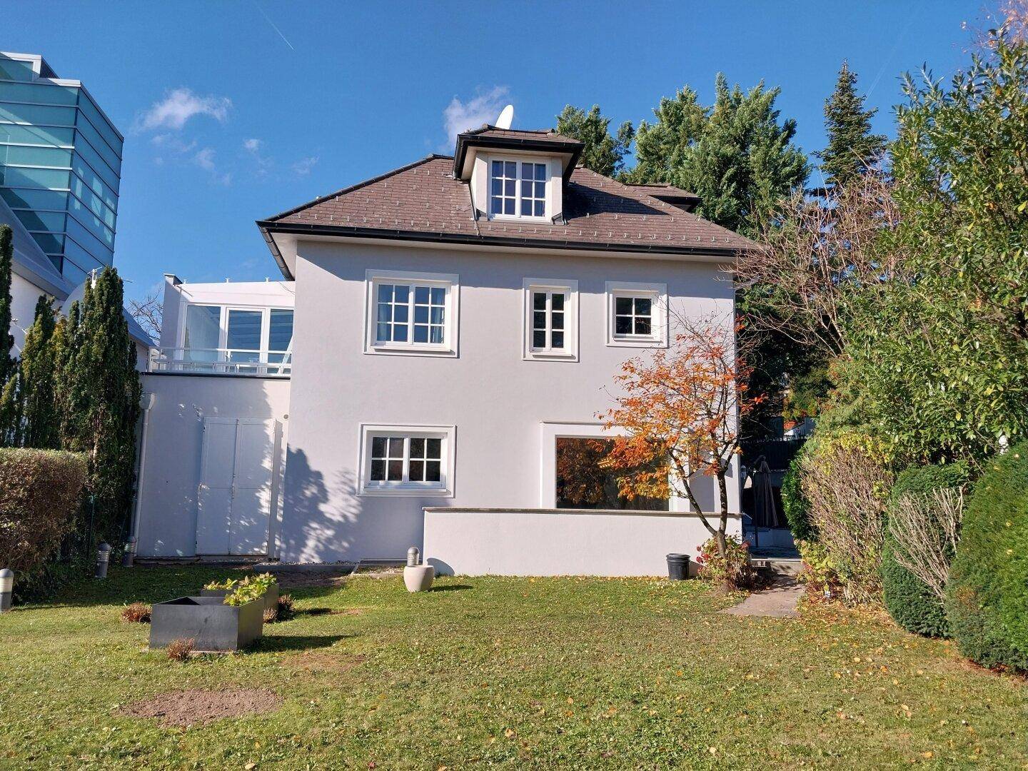 Seitenansicht der Villa mit gepflegtem Rasen und umgebenden Bäumen.