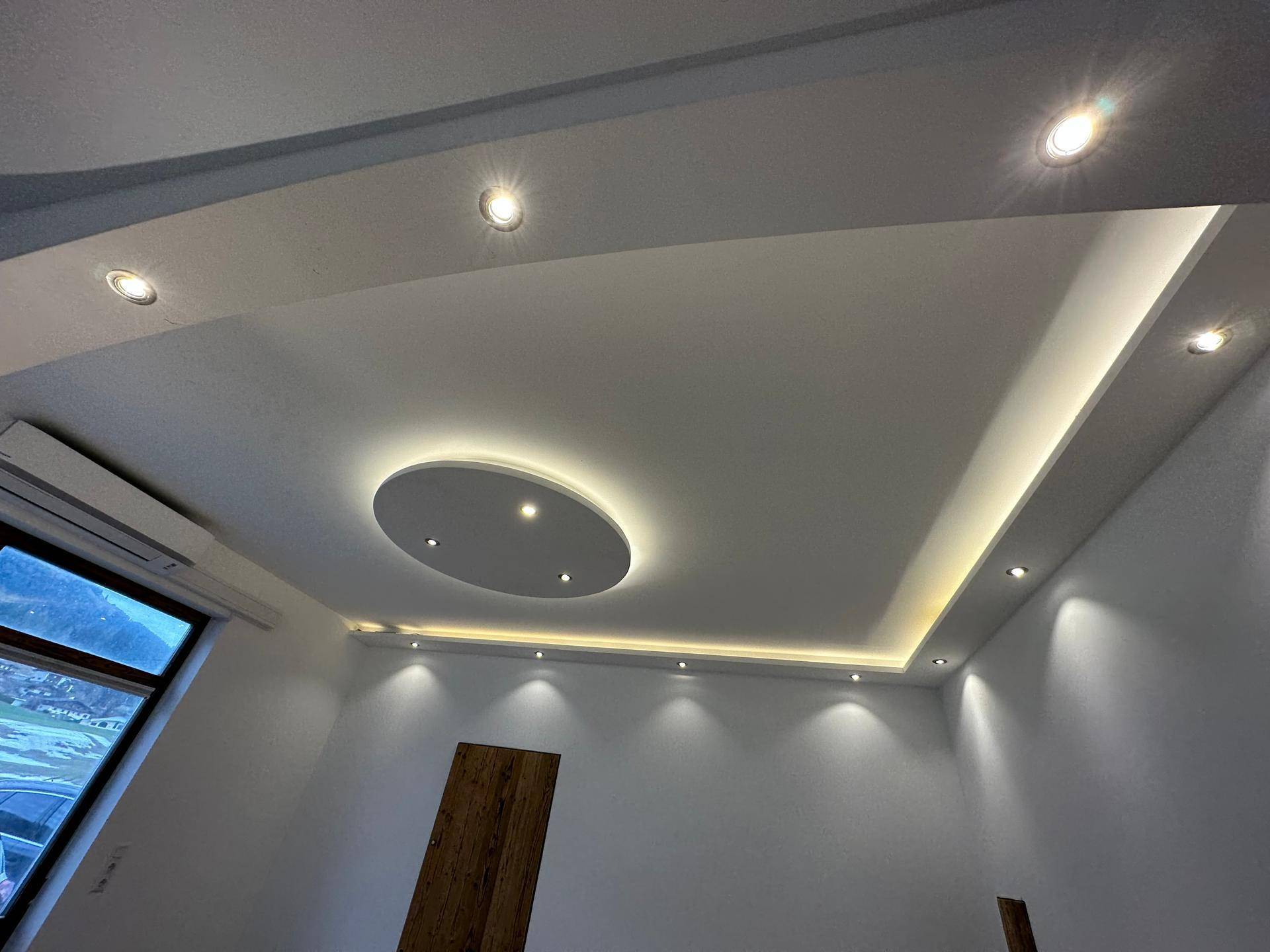 Detailaufnahme der modernen Deckenbeleuchtung mit Einbaustrahlern und indirektem Lichtband.