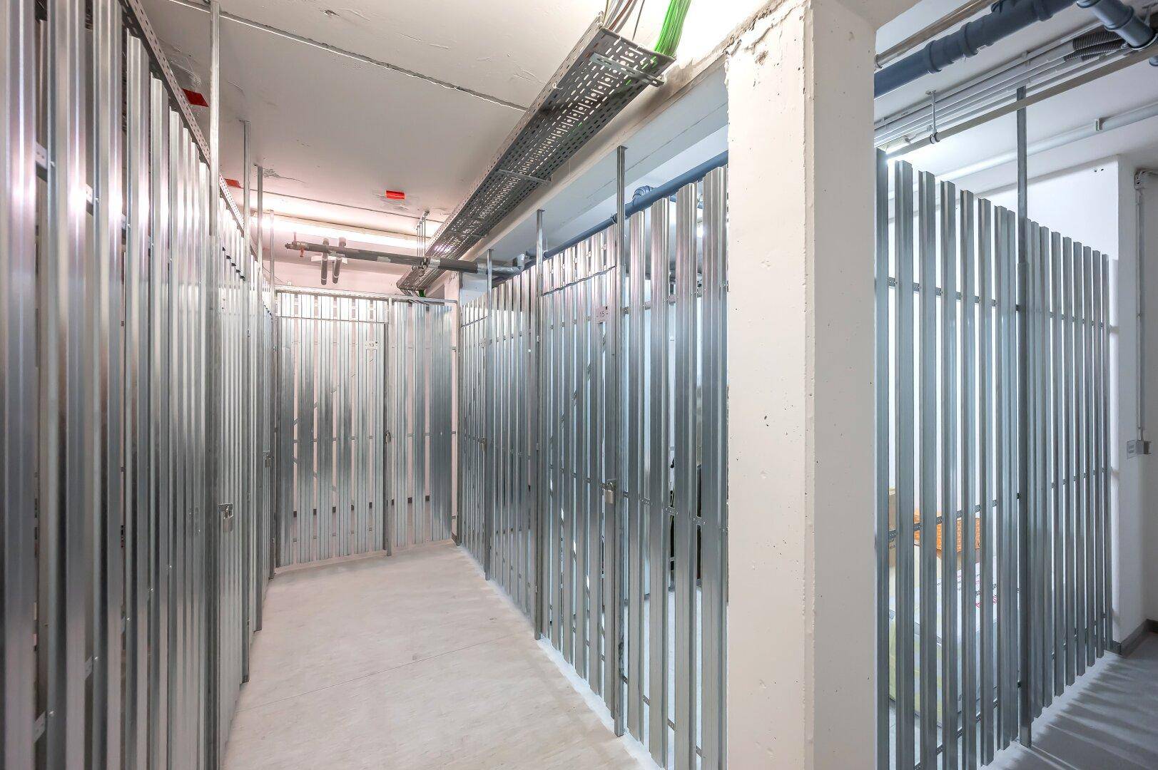 Langer Flur mit zahlreichen individuellen Kellerabteilen aus Metall für persönlichen Stauraum.