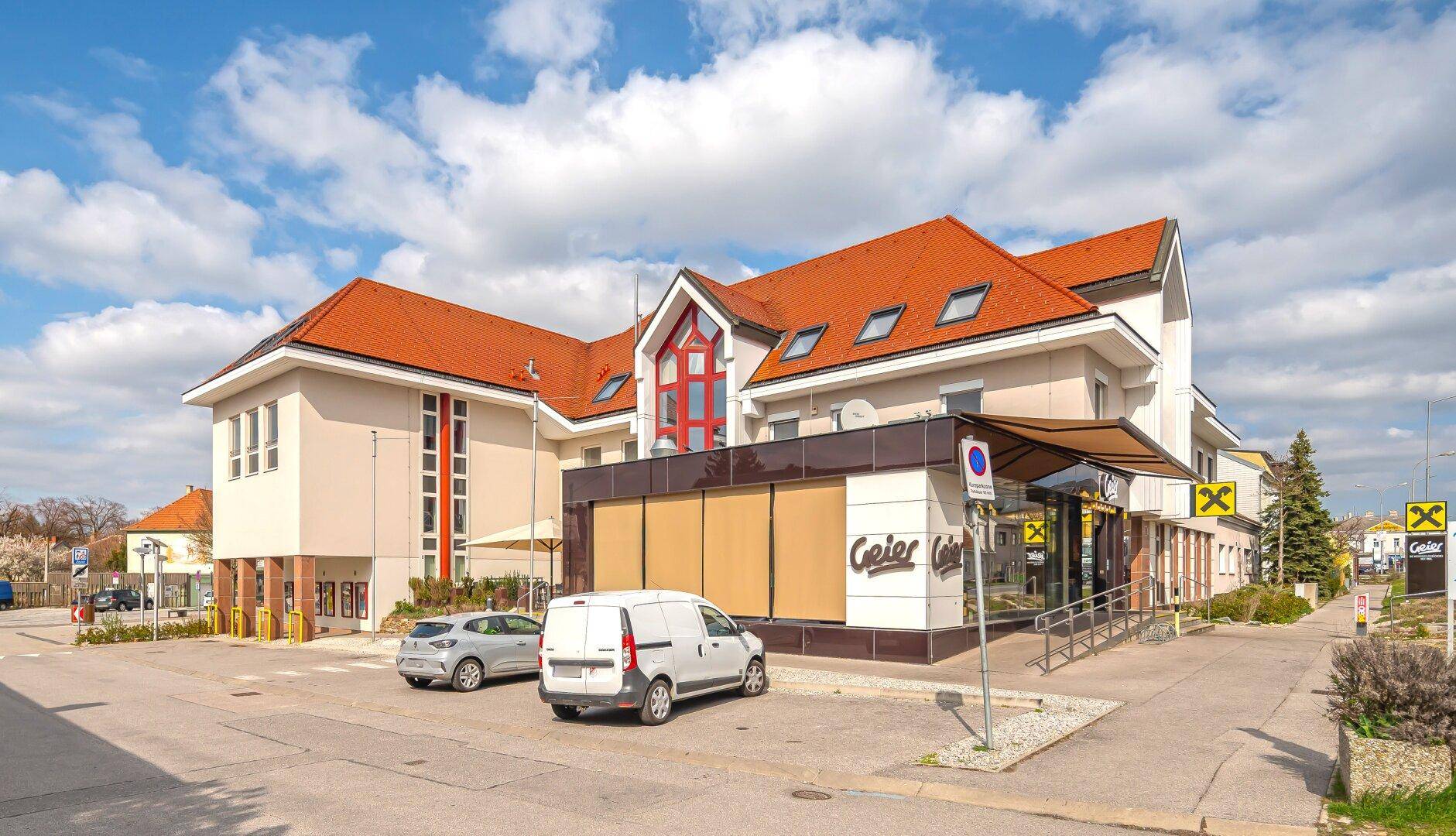 Modernes Geschäftsgebäude mit markanter Architektur und Parkplätzen an der Straße.