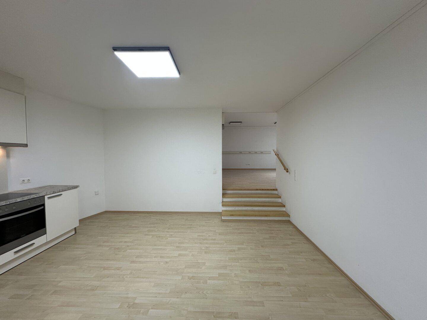 Geräumiger offener Bereich mit Laminatboden und einer Treppe, die zu weiteren Räumen führt.