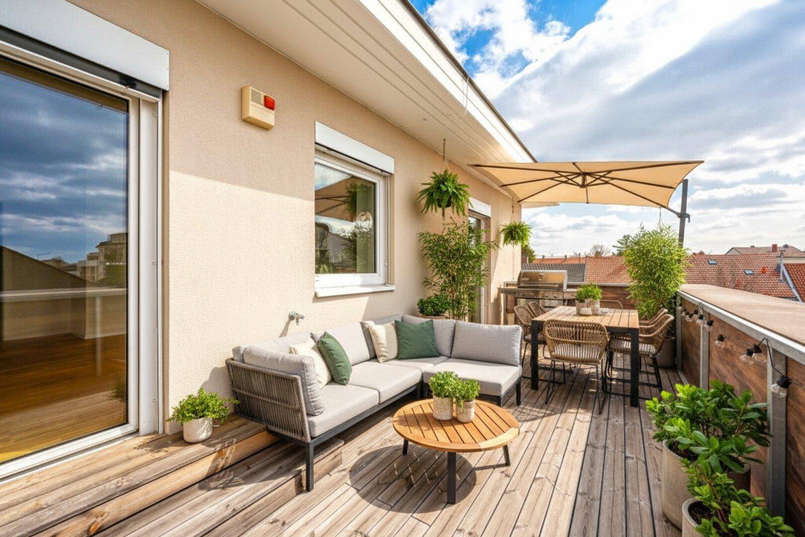 Einladende Dachterrasse mit Holzboden, bequemen Loungemöbeln und Sonnenschirm für entspannte Stunden.