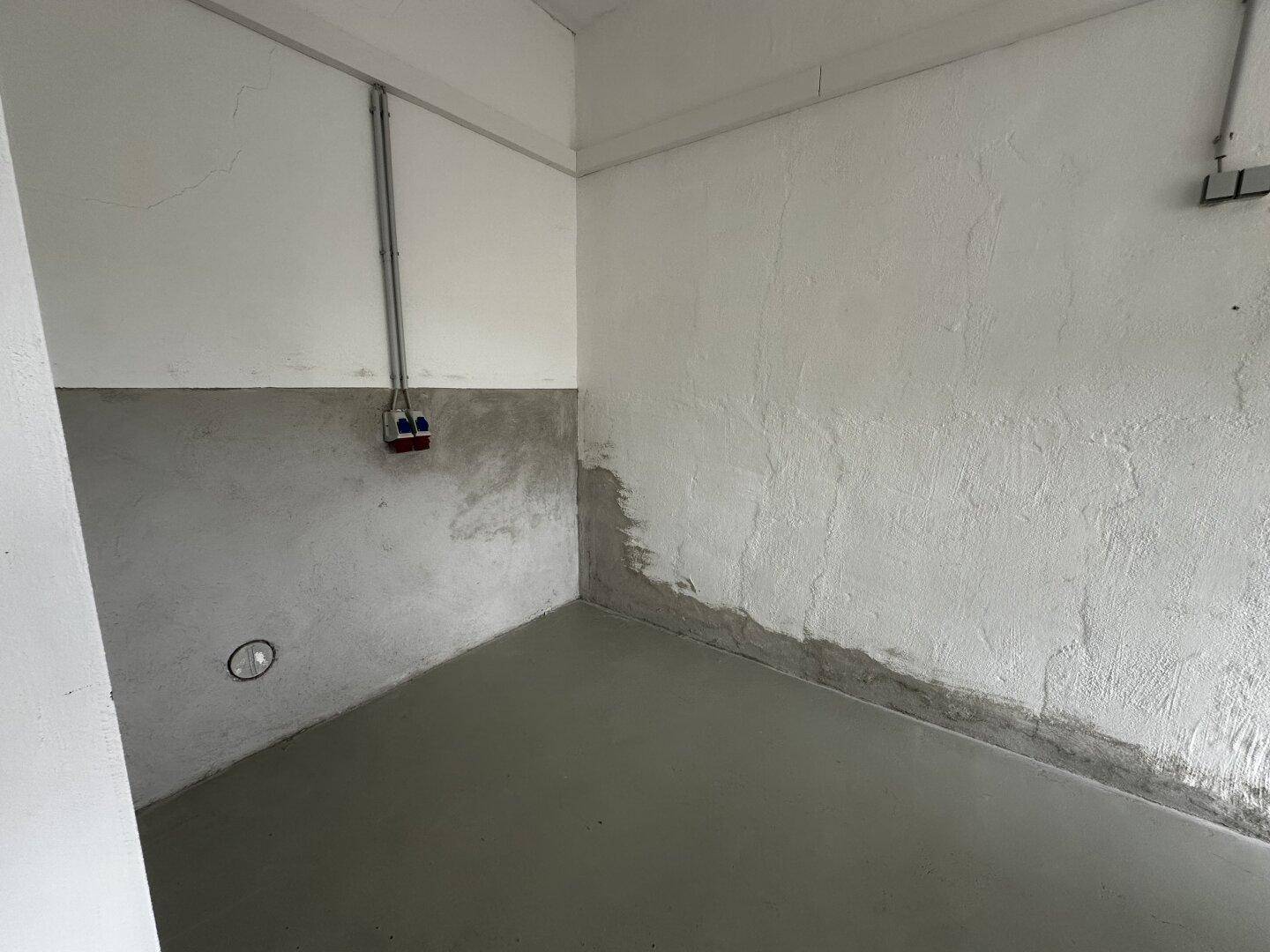 Einfacher Abstellraum mit Betonboden und teilweise verputzten Wänden, ideal für Lagerzwecke.