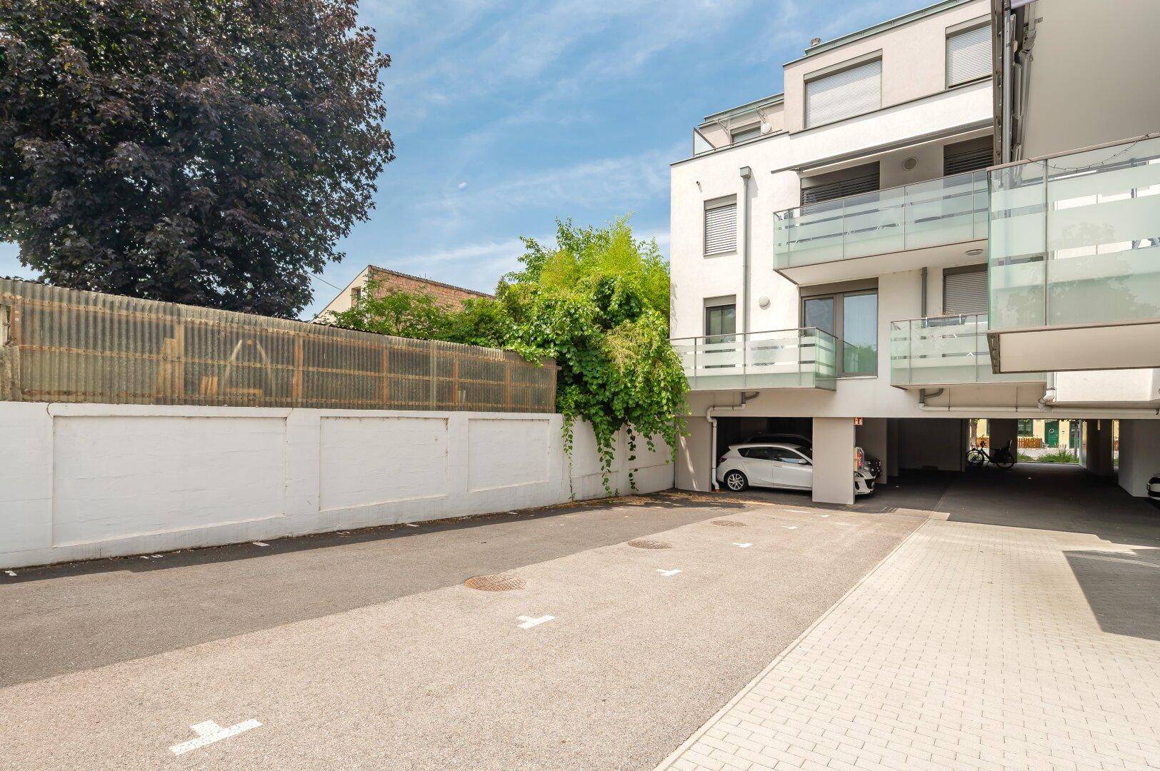 Außenansicht des Parkplatzes neben dem modernen Wohngebäude mit Grünflächen.