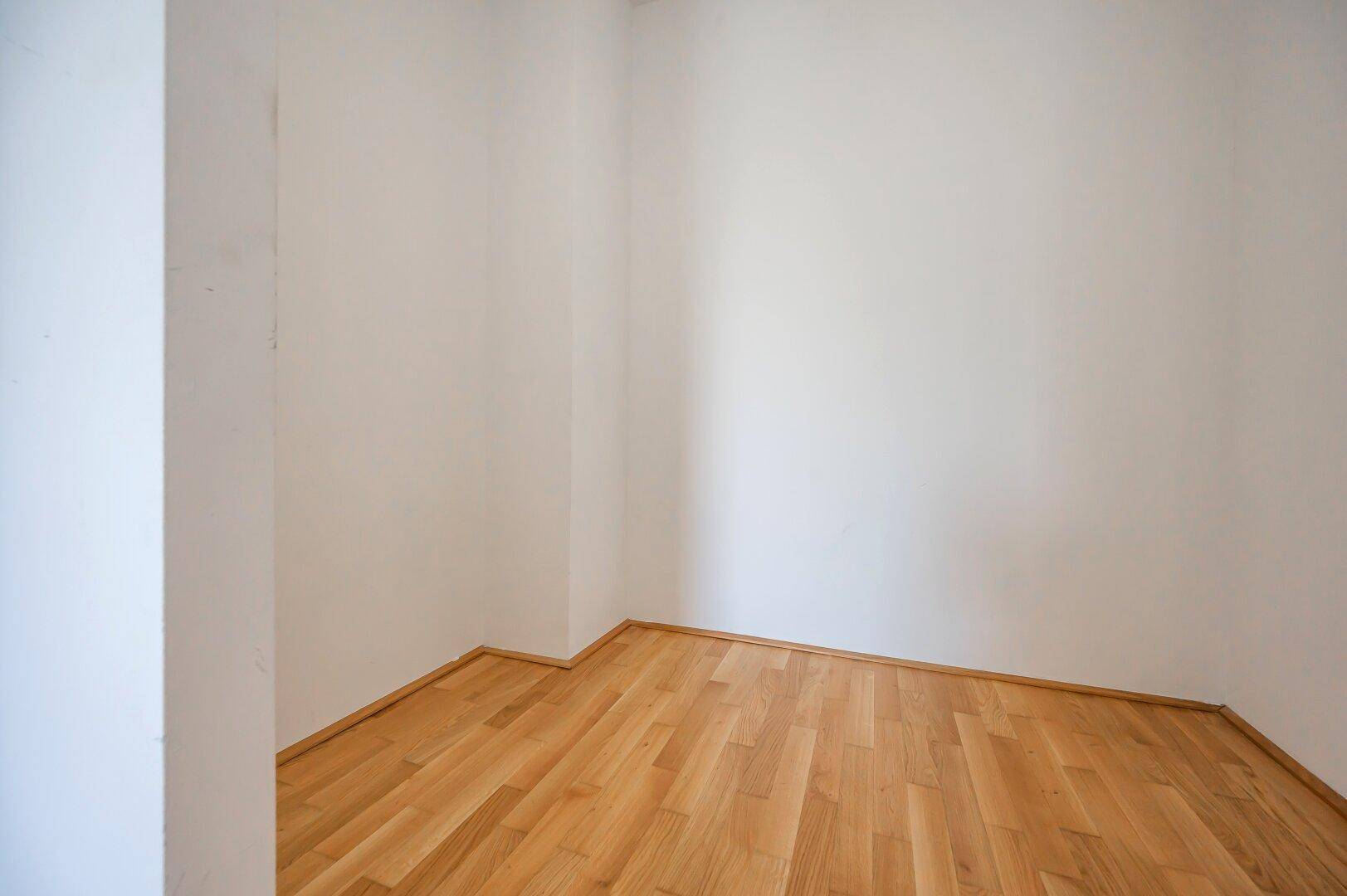 Kleiner, leerer Raum mit Parkettboden und weißen Wänden, ideal als Abstellraum oder begehbarer Kleiderschrank.