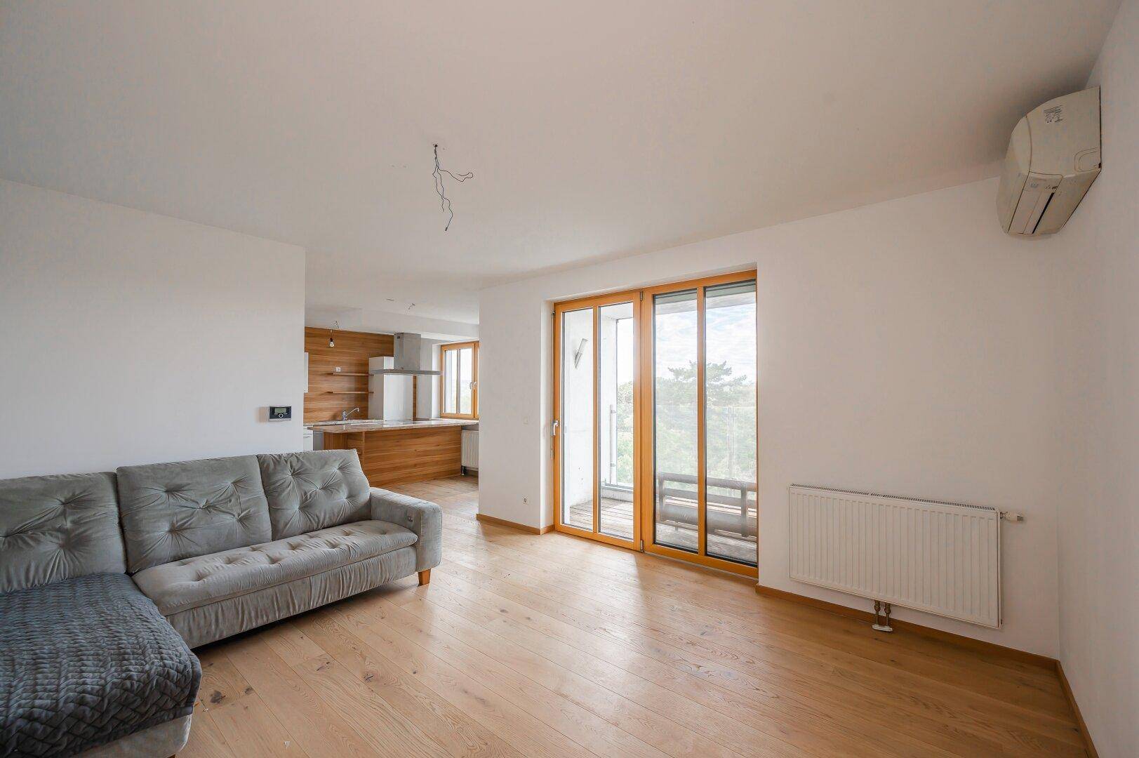 Helles Wohnzimmer mit Sofa, Klimaanlage und Zugang zu einem Balkon.