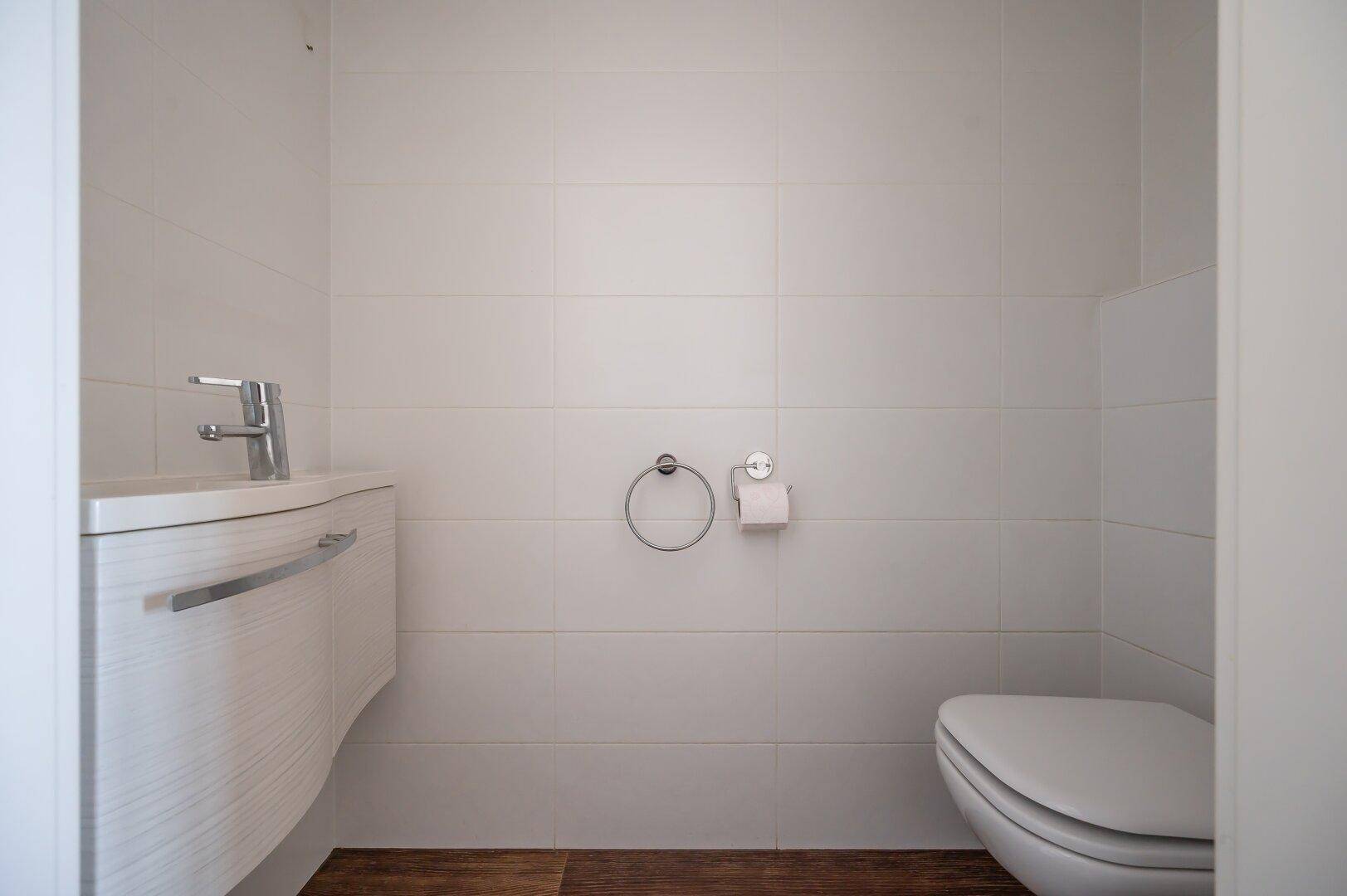 Modernes Gäste-WC mit wandhängender Toilette und kleinem Waschbecken.