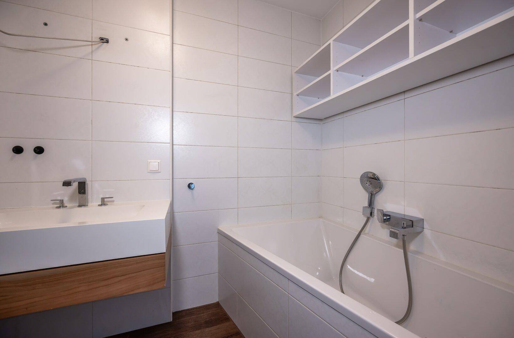 Modernes Badezimmer mit Badewanne, Waschbecken und weißen Fliesen.