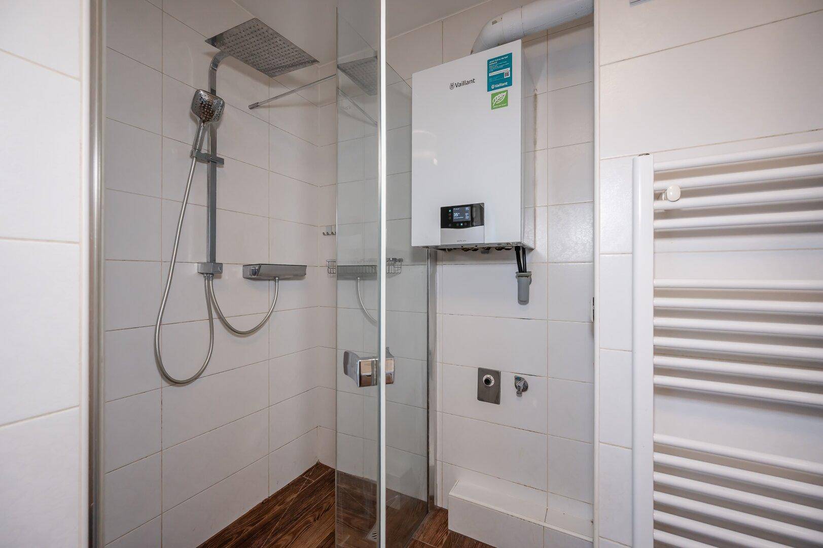 Modernes Badezimmer mit Duschkabine, Regendusche und Warmwasserboiler.