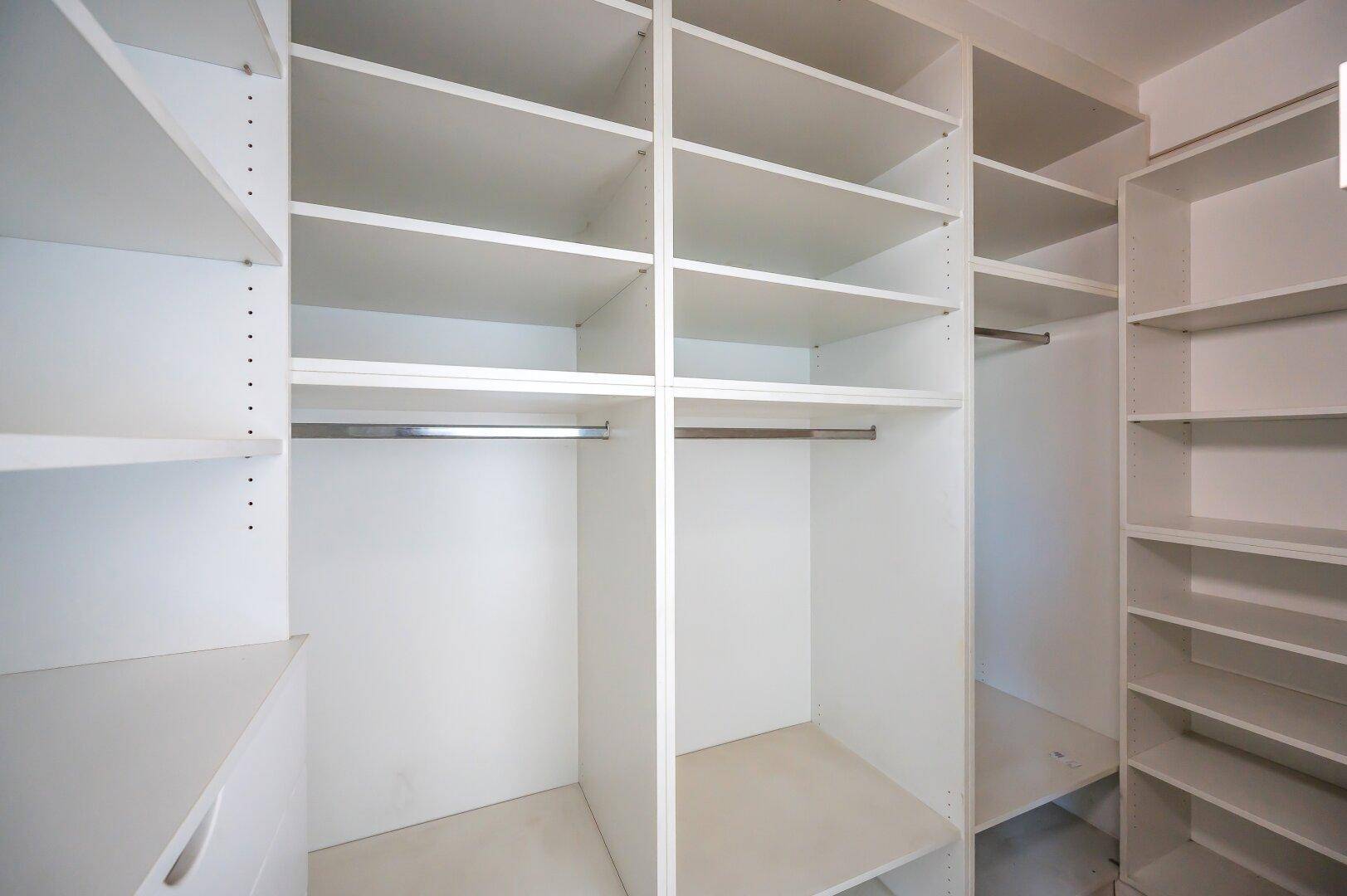 Geräumiger begehbarer Kleiderschrank mit vielen Regalen und Aufhängemöglichkeiten.
