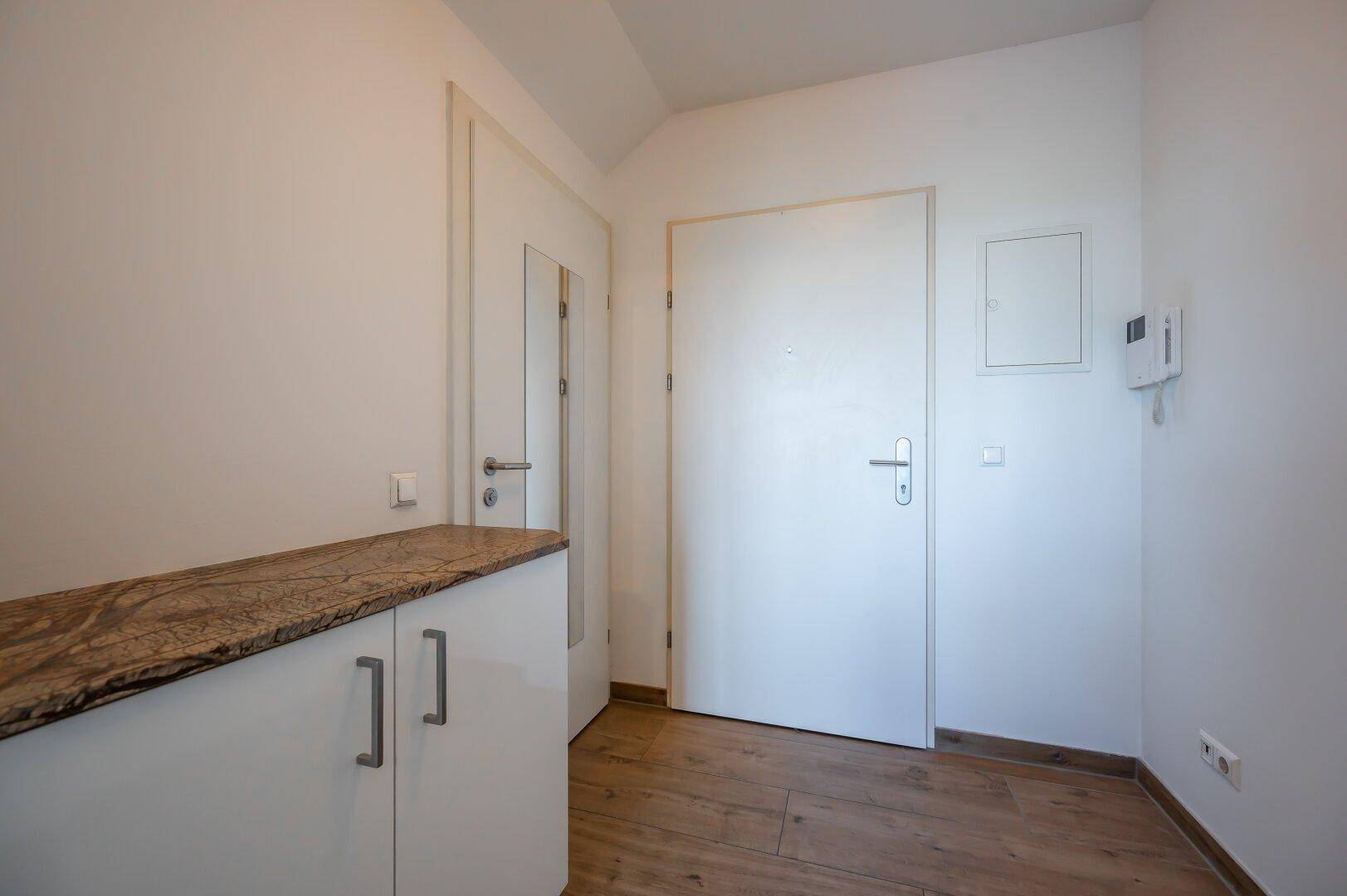 Heller Eingangsbereich mit Garderobenschrank und Sicherheitstür.