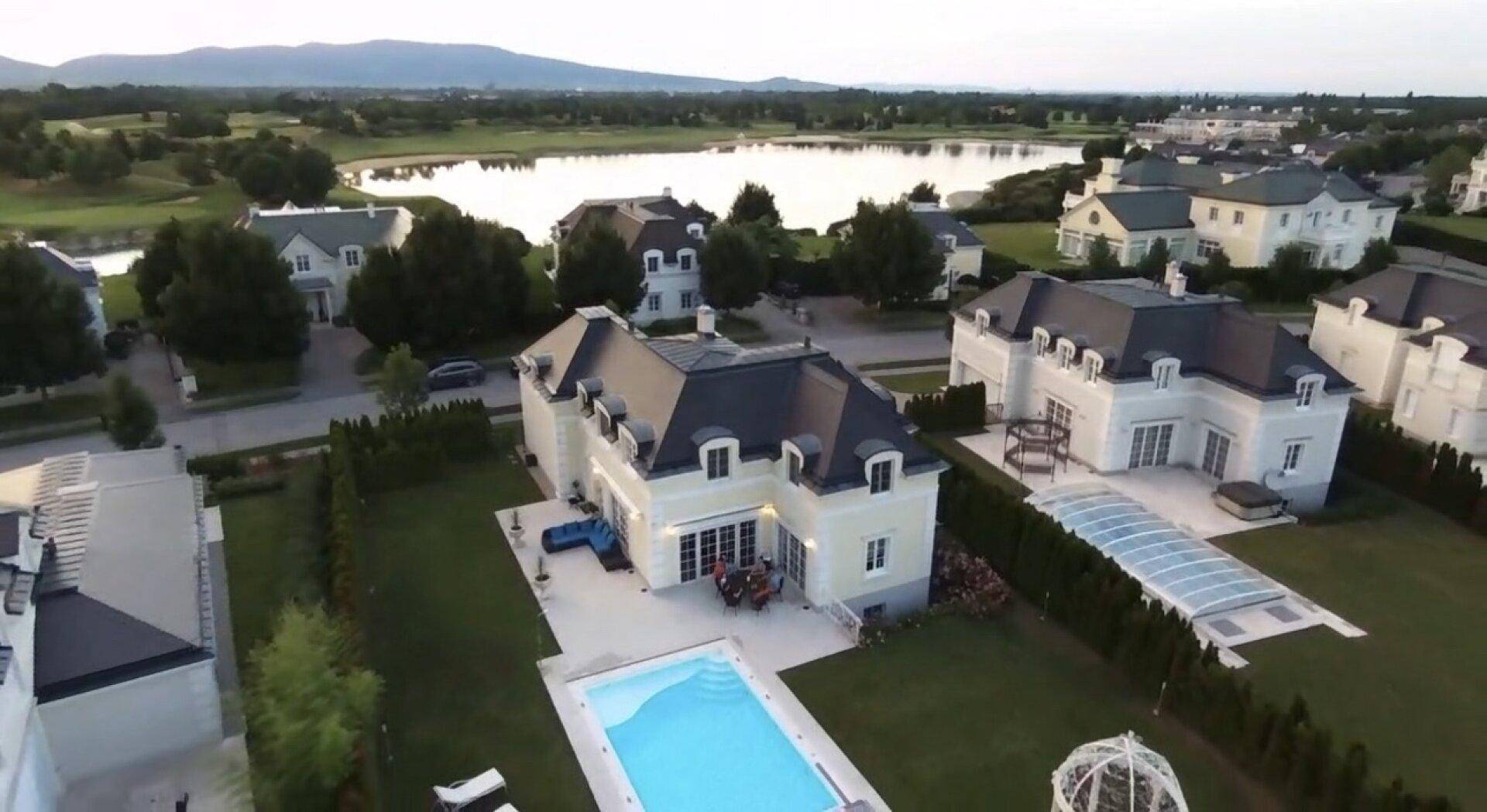 Luftaufnahme des Anwesens mit Pool, umgeben von ähnlichen Villen und einem nahegelegenen See.