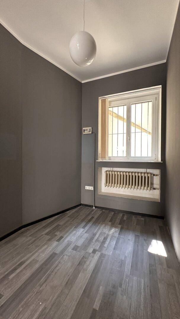Kleinerer Raum mit grau gestrichenen Wänden, Fenster und Heizkörper, geeignet als ruhiges Büro.
