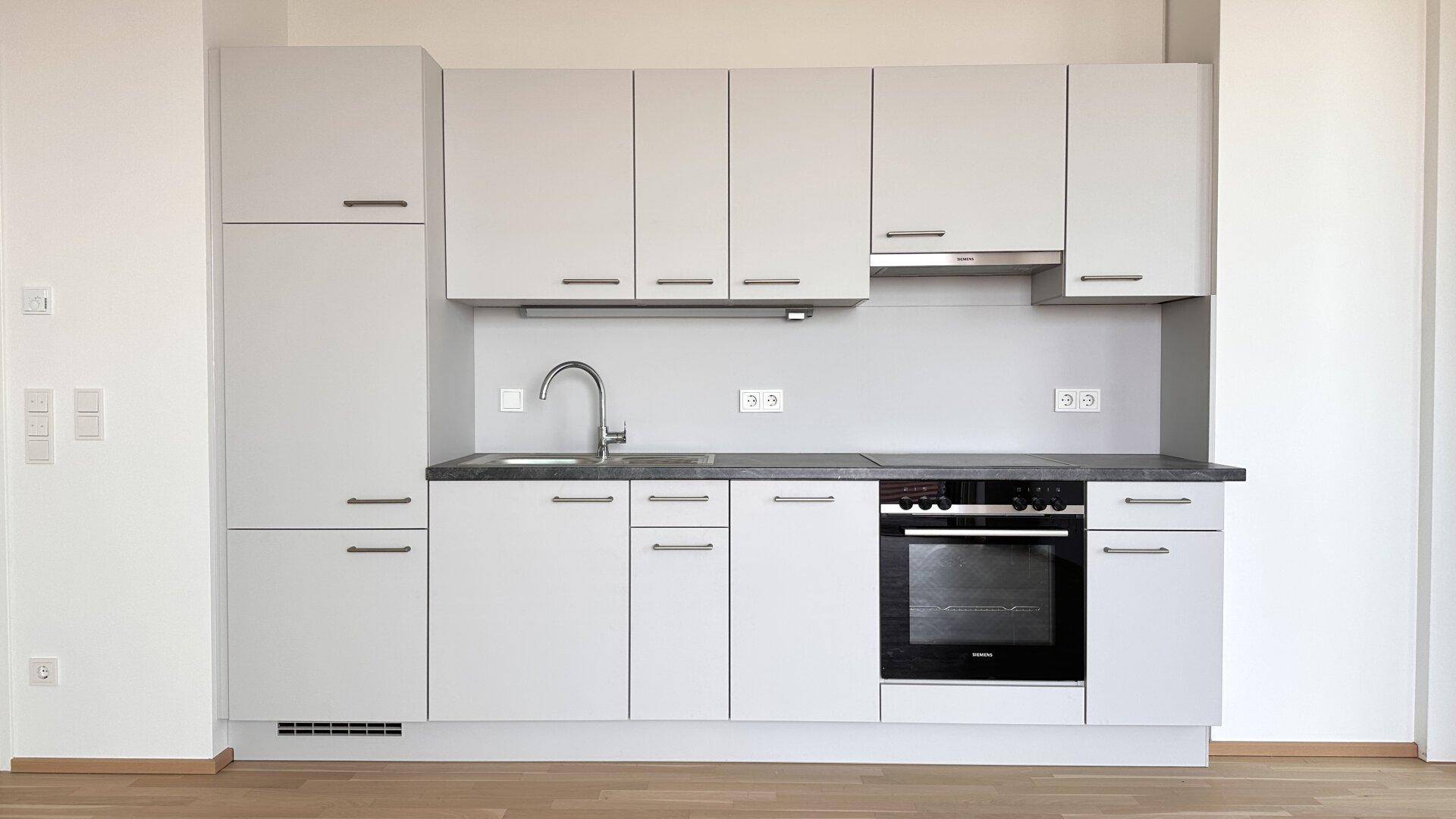 Moderne Einbauküche in hellem Grau mit integrierten Geräten und ausreichend Stauraum.