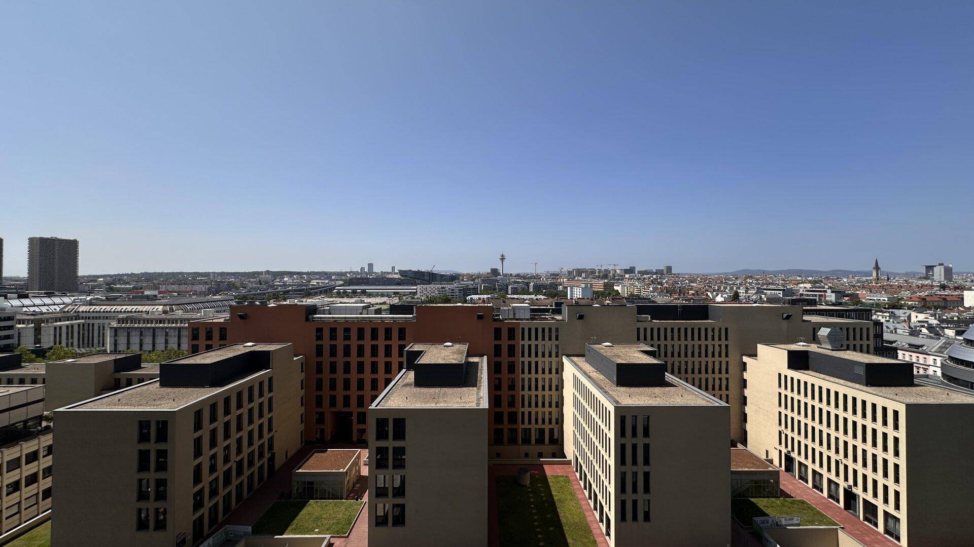 Weitläufiger Blick über die Stadt mit zahlreichen Gebäuden unter klarem blauem Himmel.