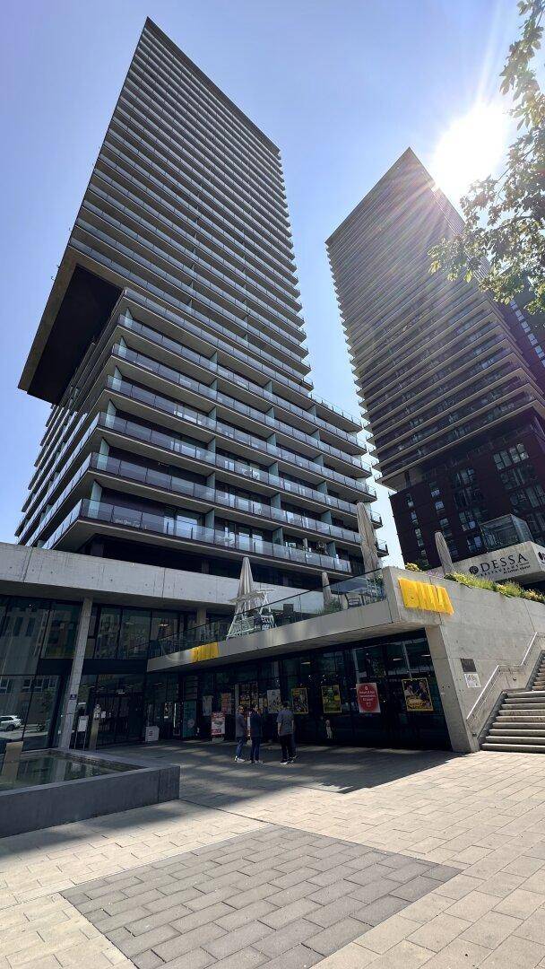 Zwei moderne Hochhäuser mit markanter Architektur und vielen Balkonen unter blauem Himmel.