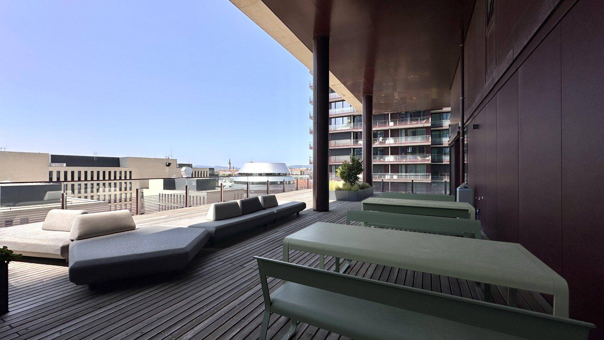 Große Dachterrasse mit modernen Lounge-Möbeln und weitem Blick über die Stadt.