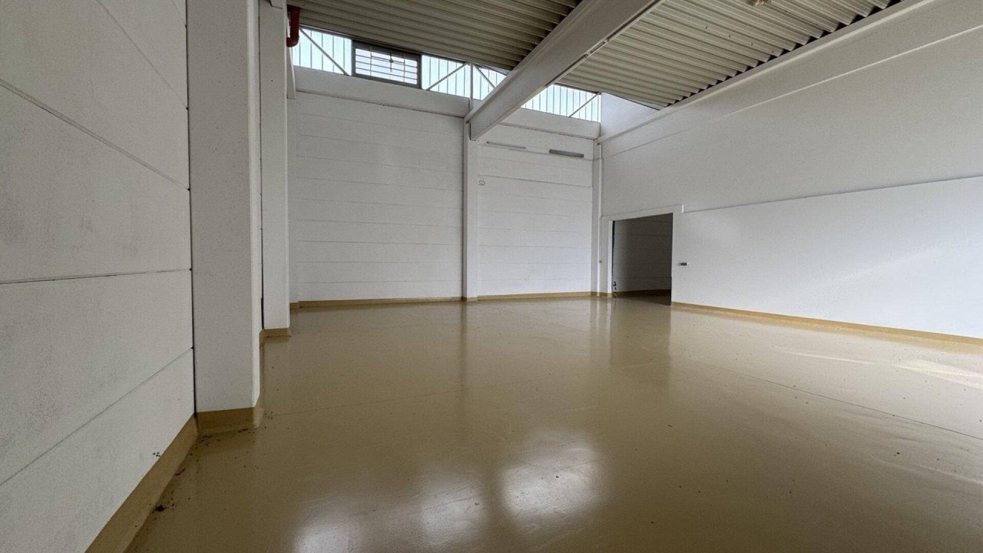 Ecke einer großen Lagerhalle mit hohen Wänden, Industrieboden und Oberlichtern für natürliche Beleuchtung.