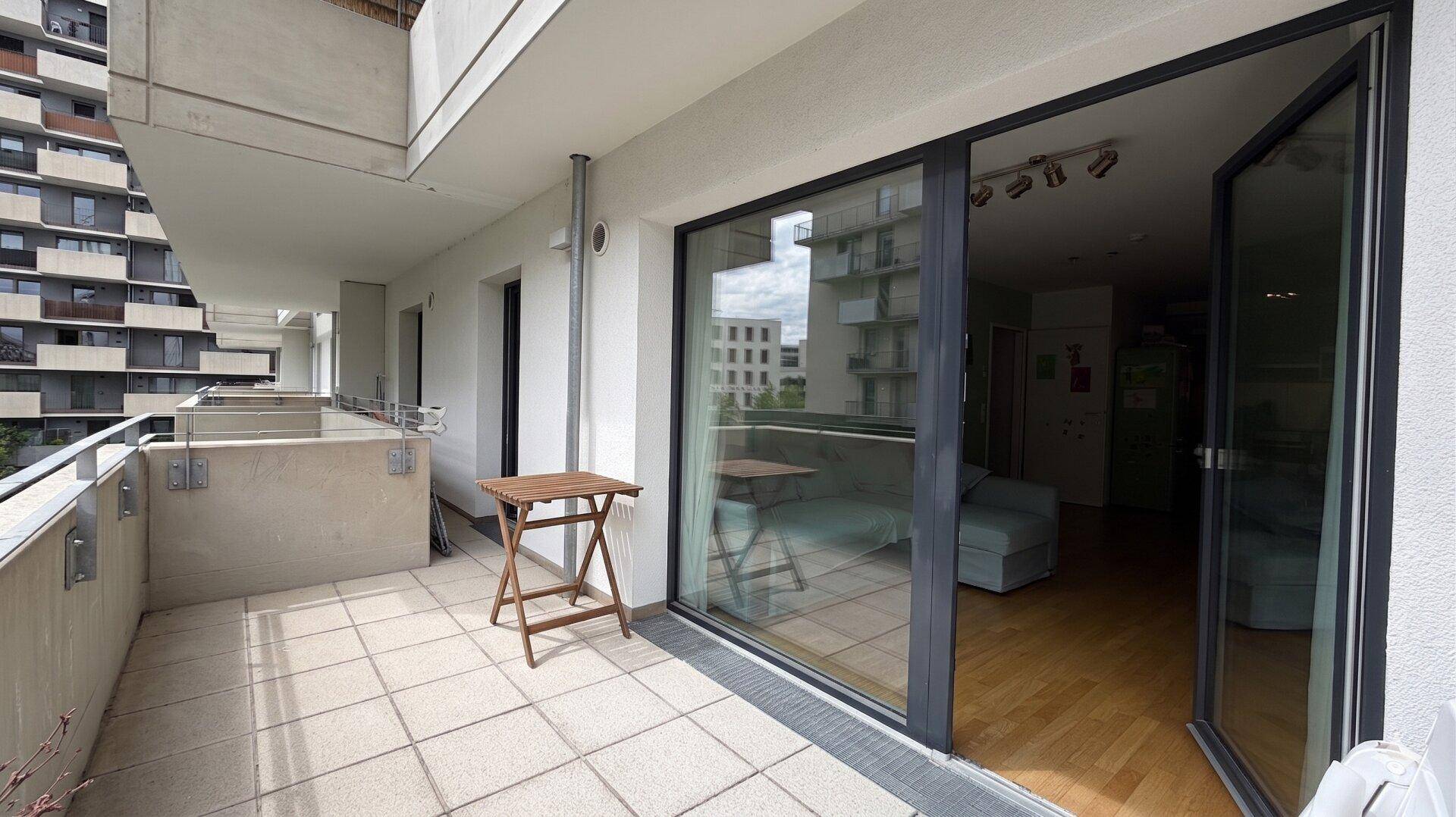 Geräumiger Balkon mit Fliesenboden und Blick auf die umliegenden Gebäude.
