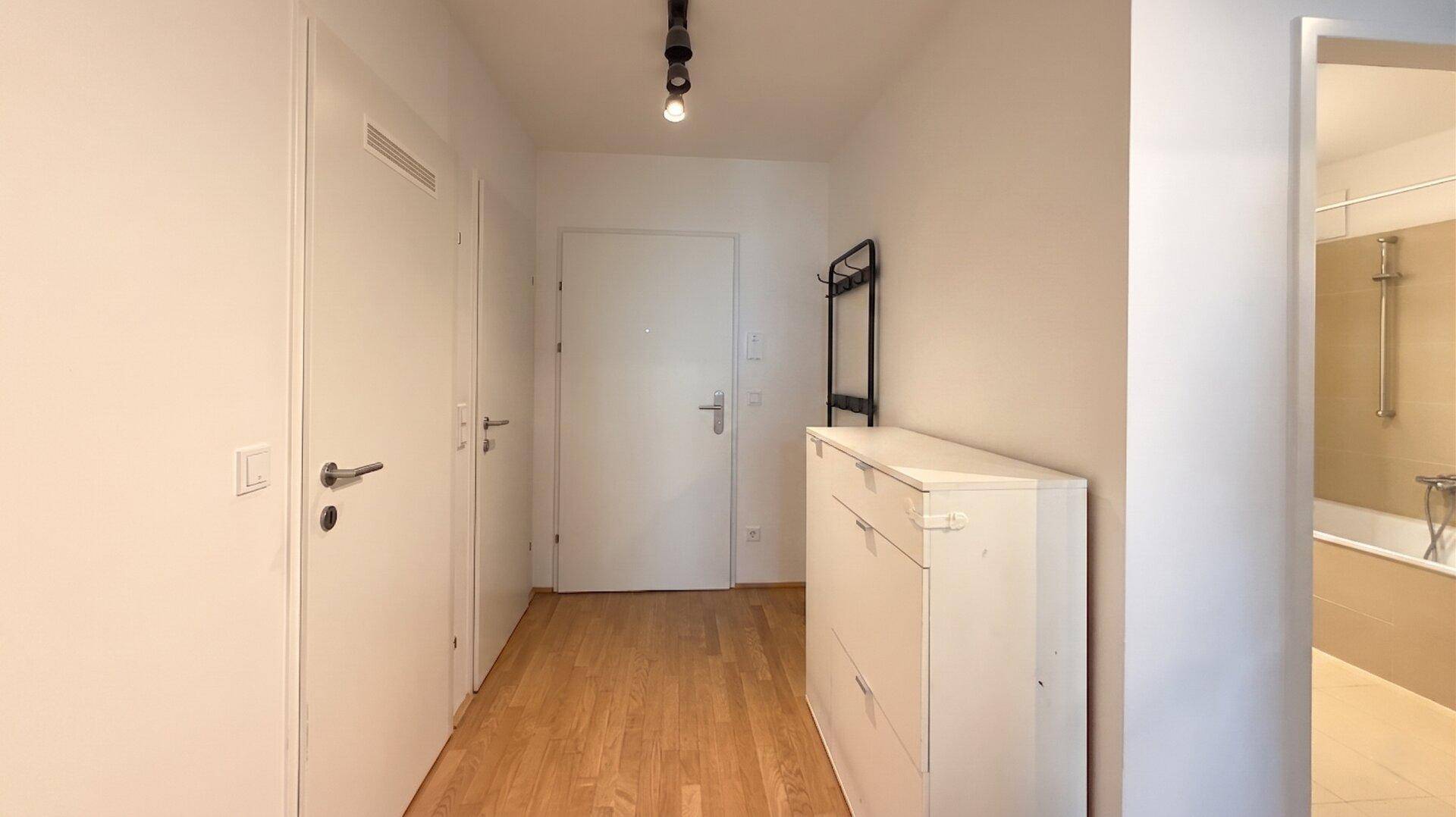 Heller Eingangsbereich mit Holzboden, Schuhschrank und Garderobe.