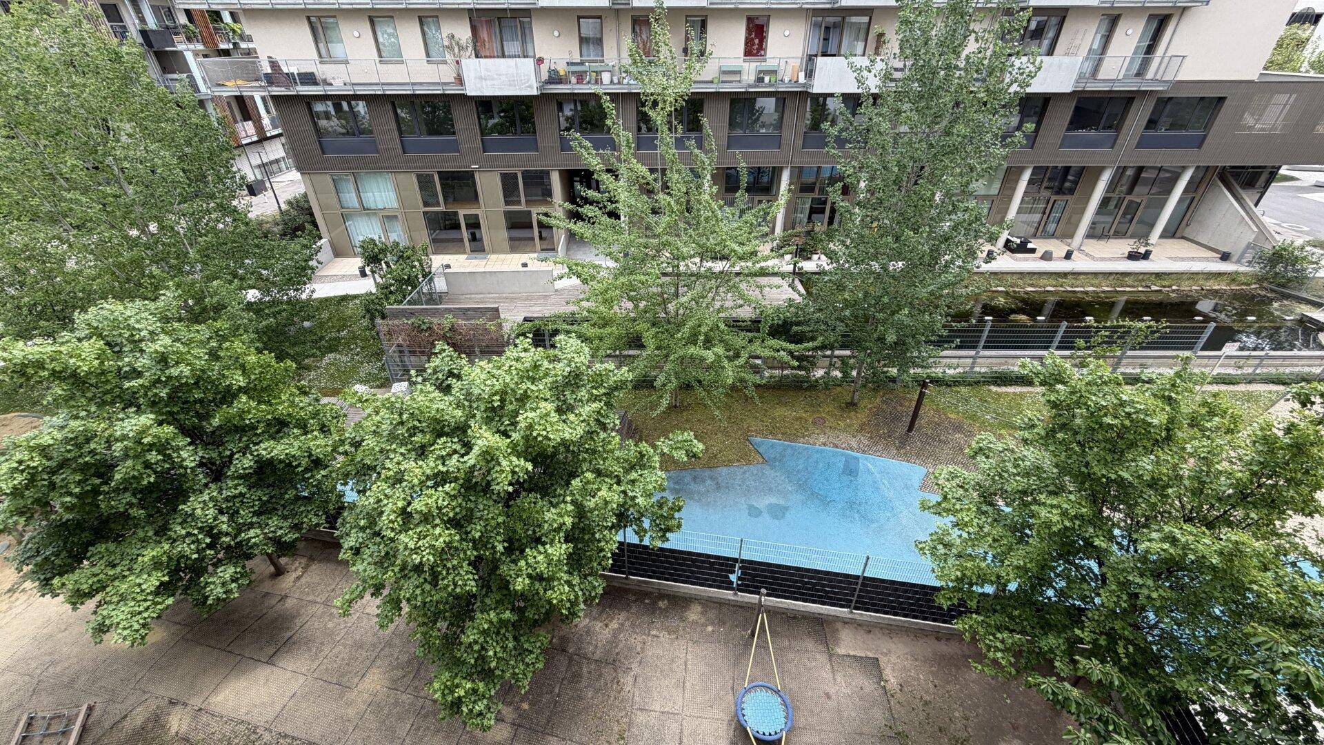 Blick von oben auf einen begrünten Innenhof mit Spielbereich und modernen Gebäuden.