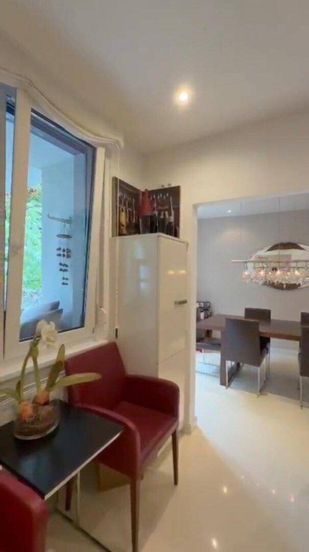 Eleganter Essbereich mit modernem Kronleuchter und Blick durch große Fenster nach draußen.