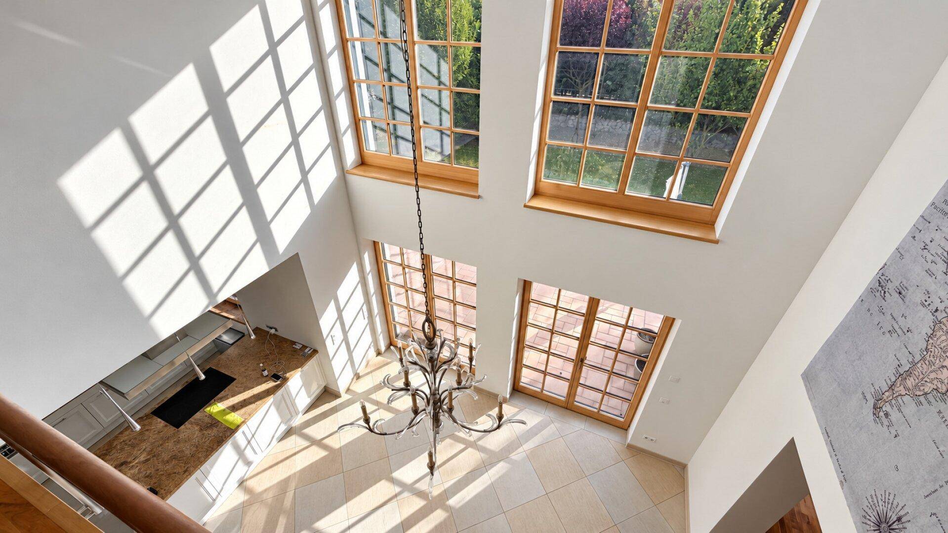Lichtdurchfluteter Wohnbereich mit hohen Decken, großen Fenstern und elegantem Kronleuchter.