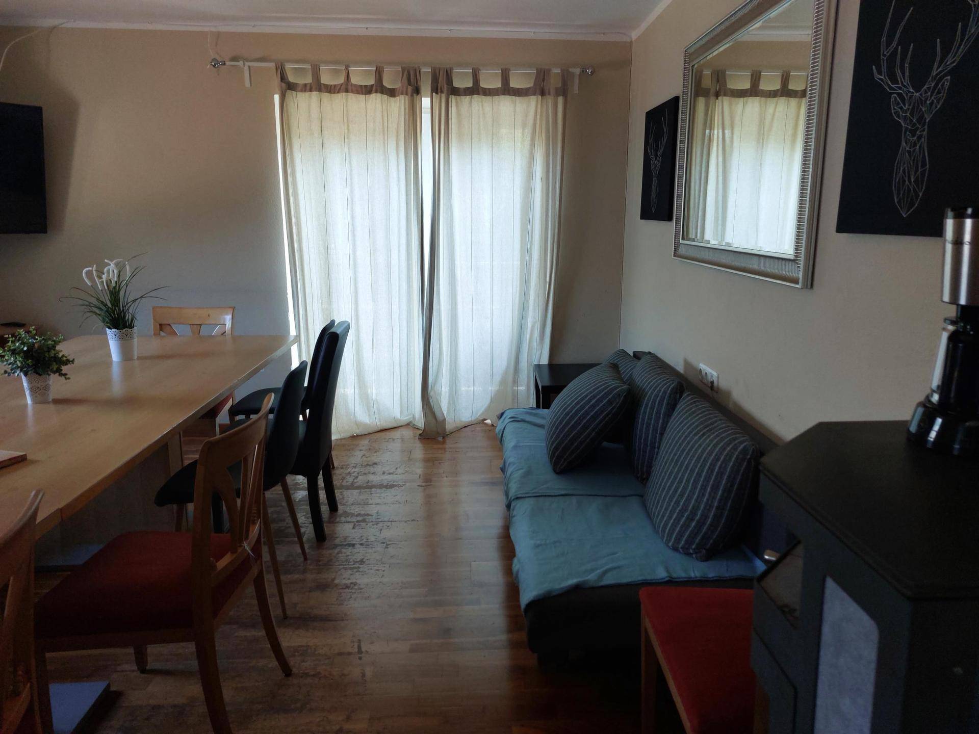 Wohnbereich mit Sofa, Esstisch und Zugang zu einem Außenbereich.