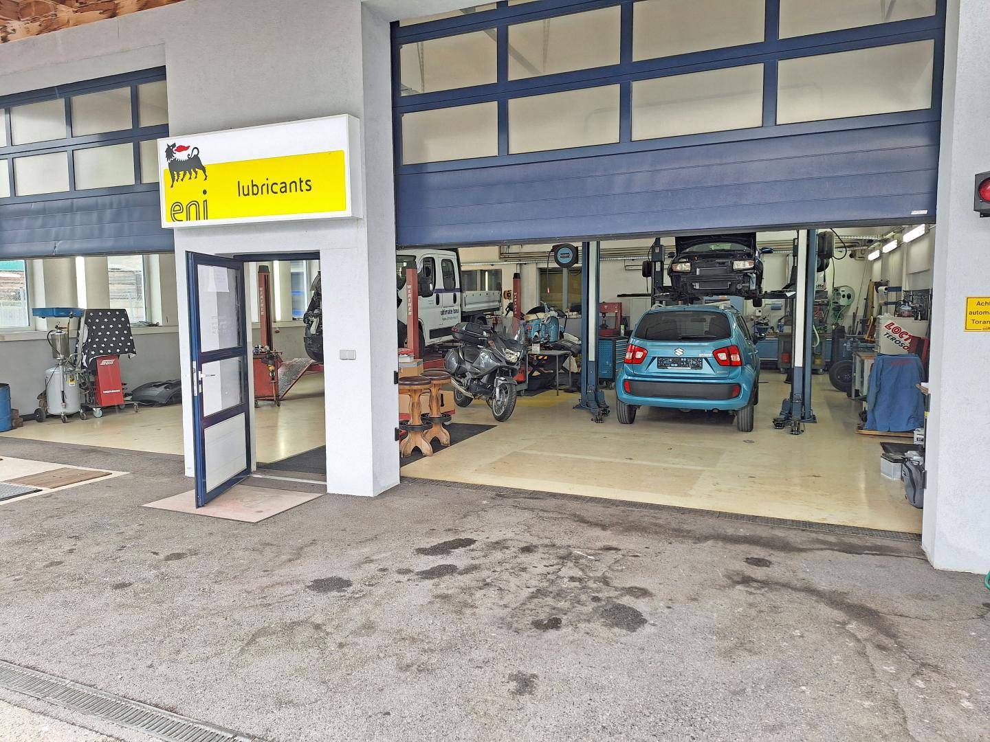 Außenansicht des Eingangs einer KFZ-Werkstatt mit geöffnetem Garagentor und Blick ins Innere.