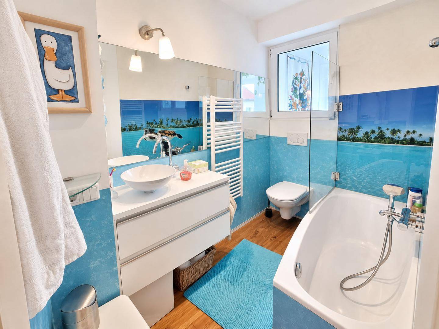 Badezimmer mit Badewanne, Waschbecken und blauen Wandfliesen im maritimen Stil.