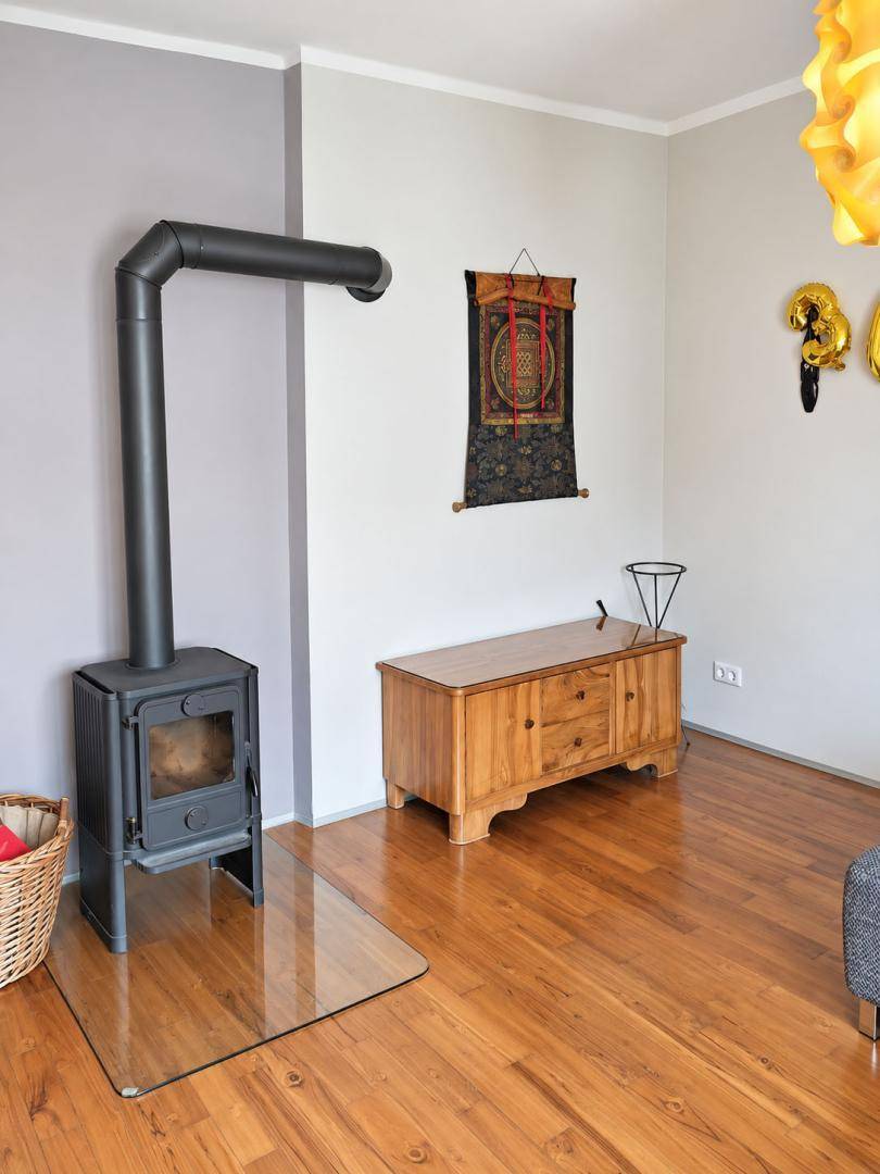 Wohnzimmer mit modernem Holzofen, Holzboden und schlichter Wandgestaltung.