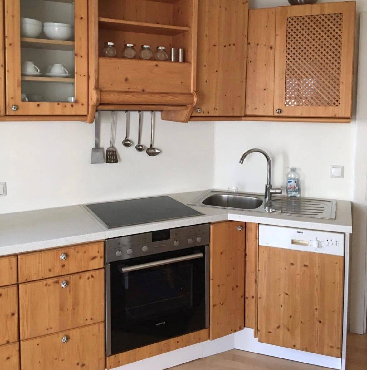 Funktionale Küche mit Holzschränken, integrierten Geräten und Spülbecken in Eckanordnung.