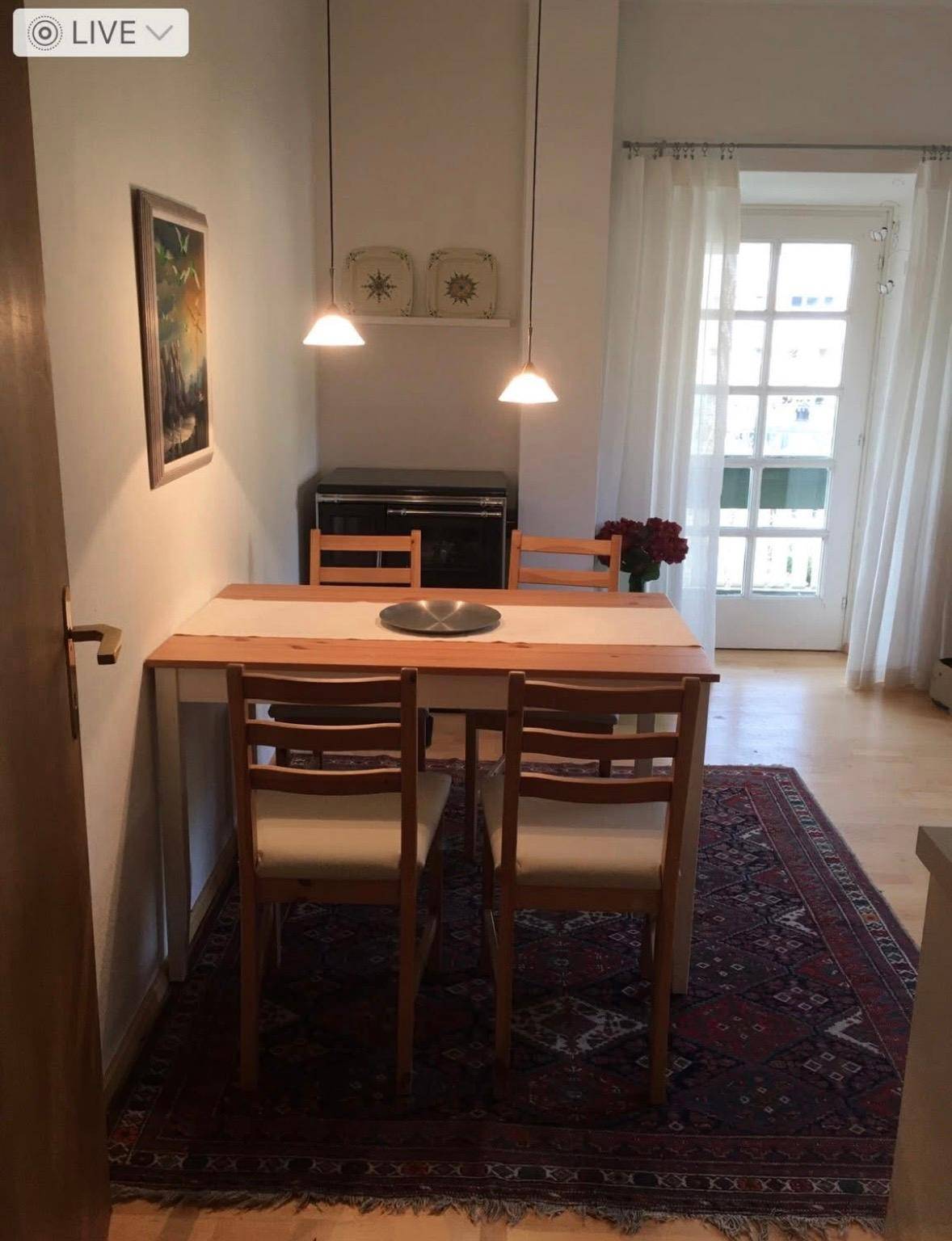 Gemütlicher Essbereich mit Holztisch und Stühlen, Teppich und Zugang zu einem Außenbereich.