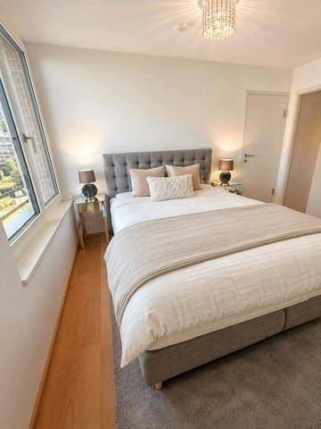 Gemütliches Schlafzimmer mit Doppelbett, Teppichboden und großem Fenster für viel Tageslicht.