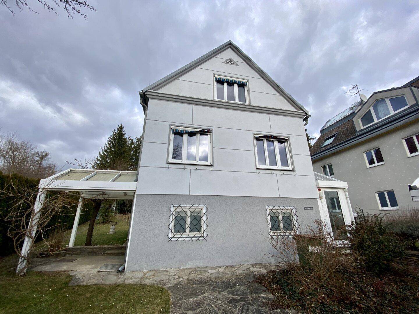 Vorderansicht des Hauses mit Fassade, Fenstern und überdachtem Eingangsbereich.