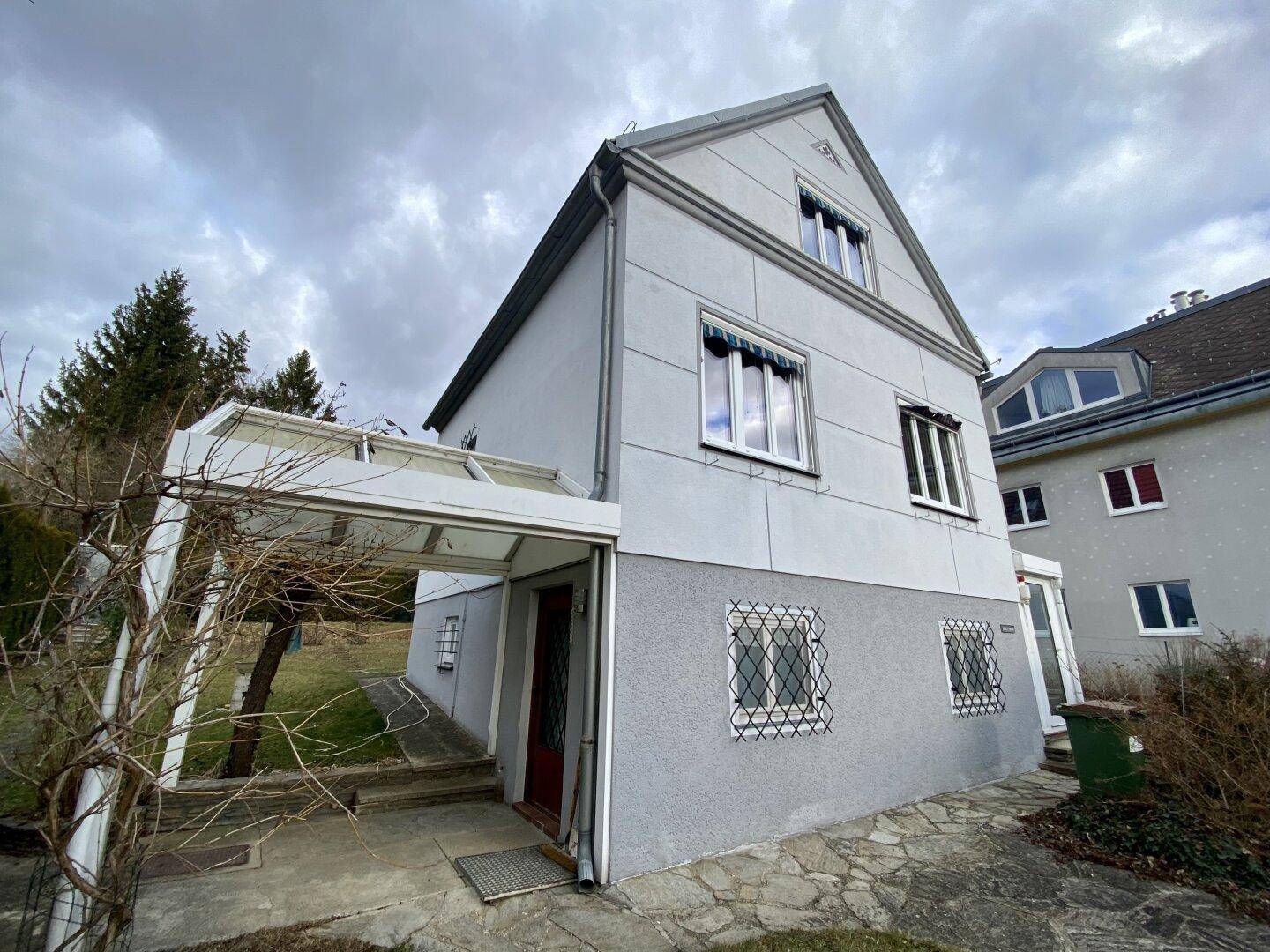 Seitenansicht des Hauses mit Eingangsbereich und überdachtem Zugang.