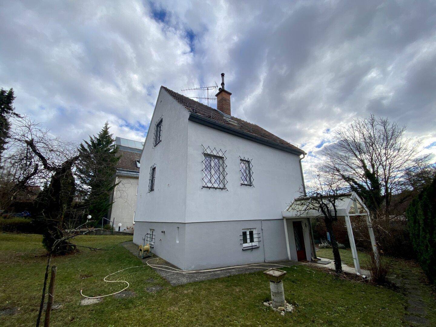 Seitenansicht des Hauses mit vergitterten Fenstern und Gartenbereich.