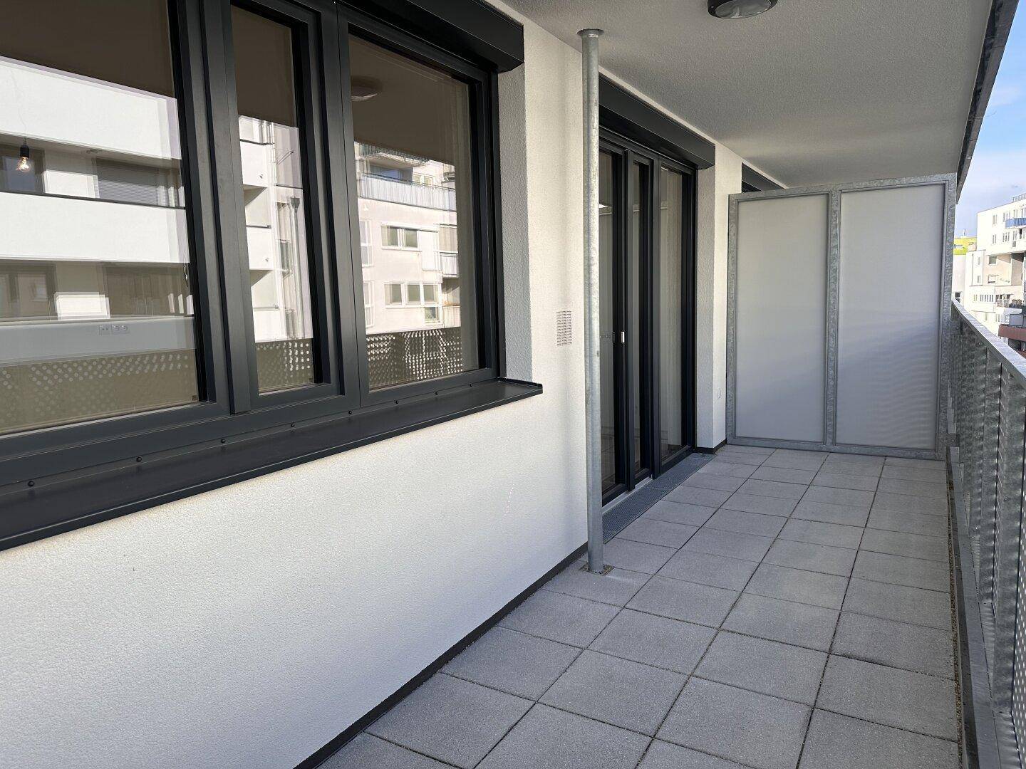 Geräumiger Balkon mit Fliesenboden und modernen Fenstern, ideal für Entspannung.