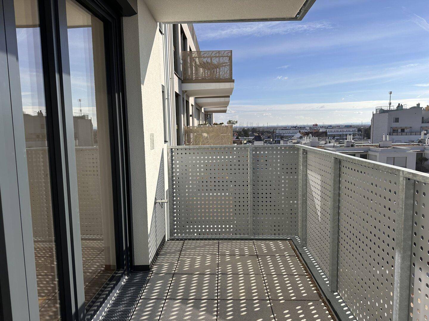 Geräumiger Balkon mit perforiertem Metallgeländer und Fliesenboden, bietet einen weiten Ausblick.