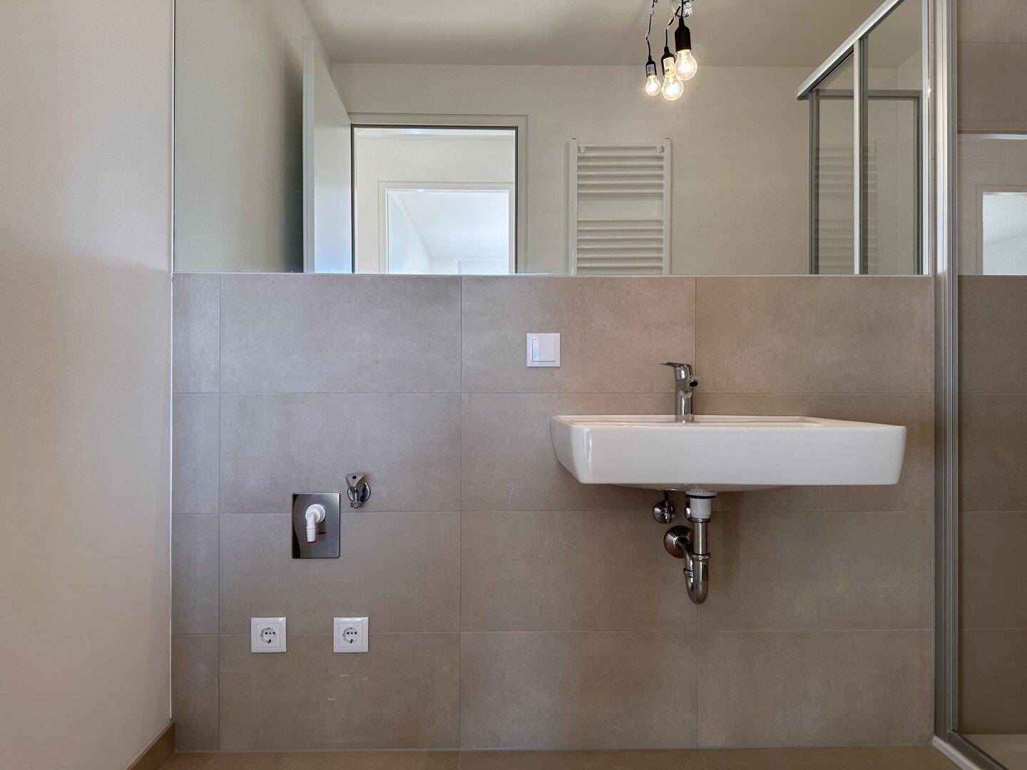 Modernes Badezimmer mit Waschbecken und großem Spiegel, in neutralen Farben und klarem Design.