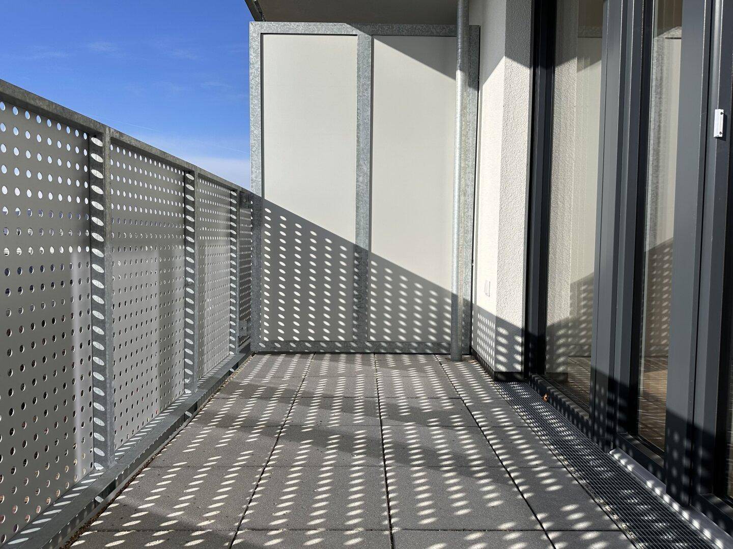 Geräumiger Balkon mit modernem Metallgeländer und viel Sonnenlicht.
