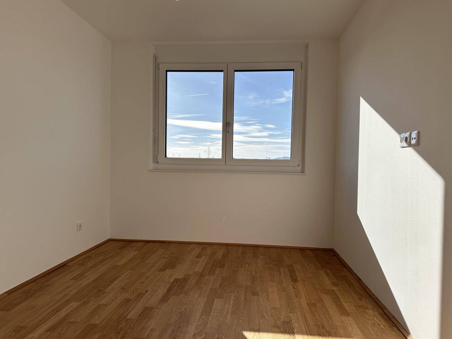 Sonniger Raum mit Parkettboden und Fenster, ideal als Schlaf- oder Arbeitszimmer.