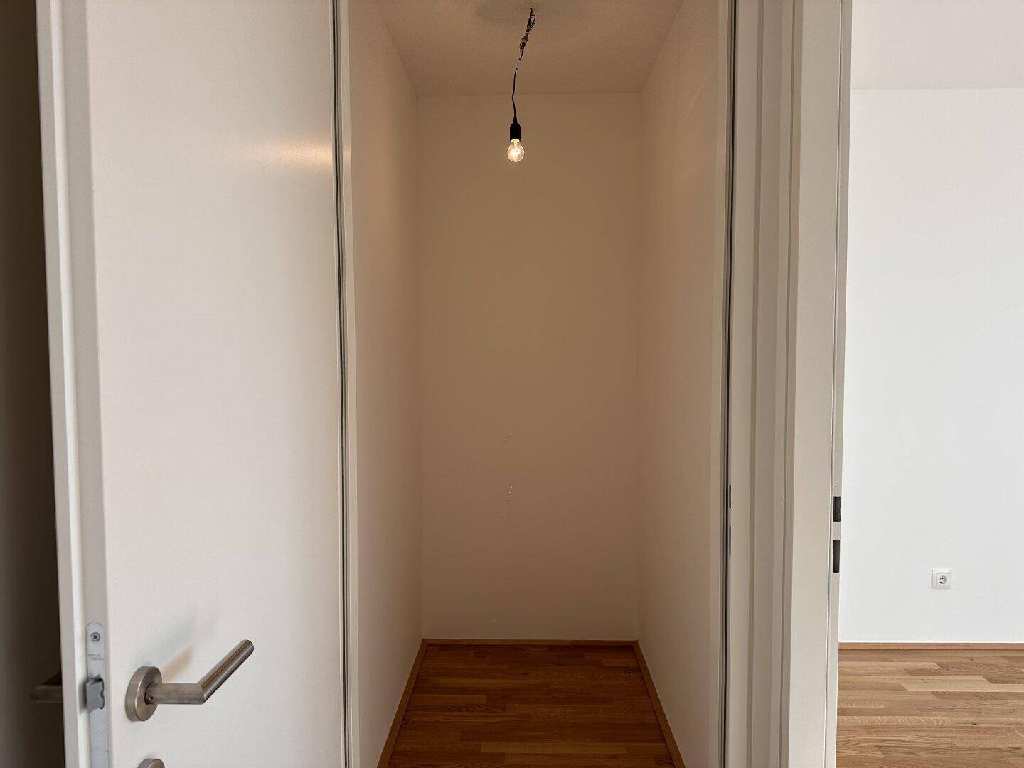 Kleiner Abstellraum mit Holzboden und einfacher Beleuchtung, ideal für zusätzlichen Stauraum.