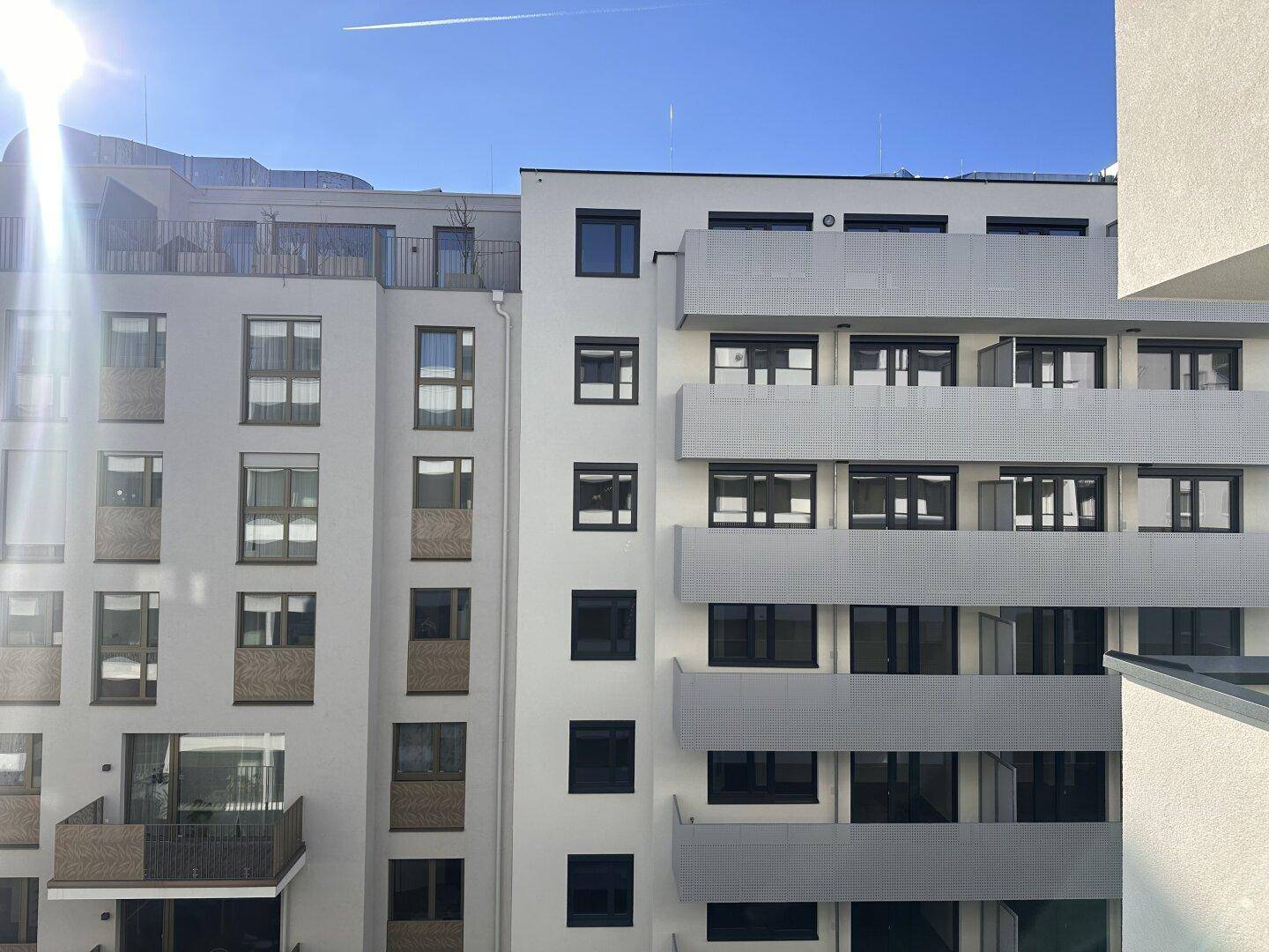 Ansicht von modernen Wohngebäuden mit Balkonen und großen Fenstern unter blauem Himmel.