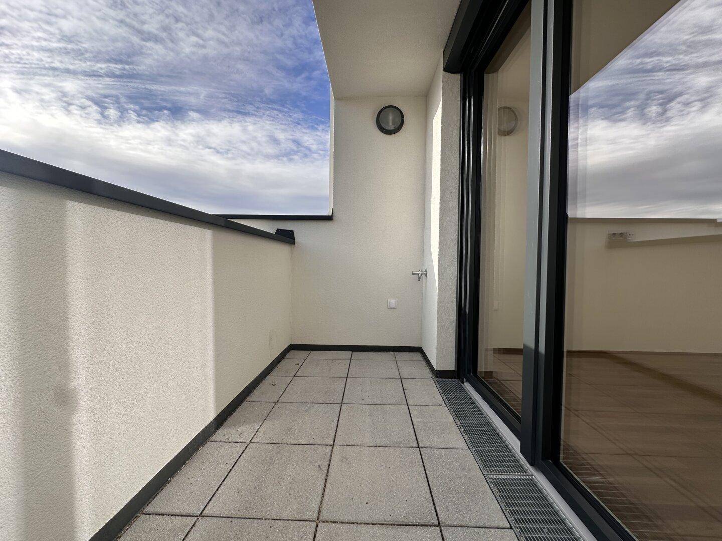 Langer, schmaler Balkon mit Fliesenboden und Blick auf die Umgebung.